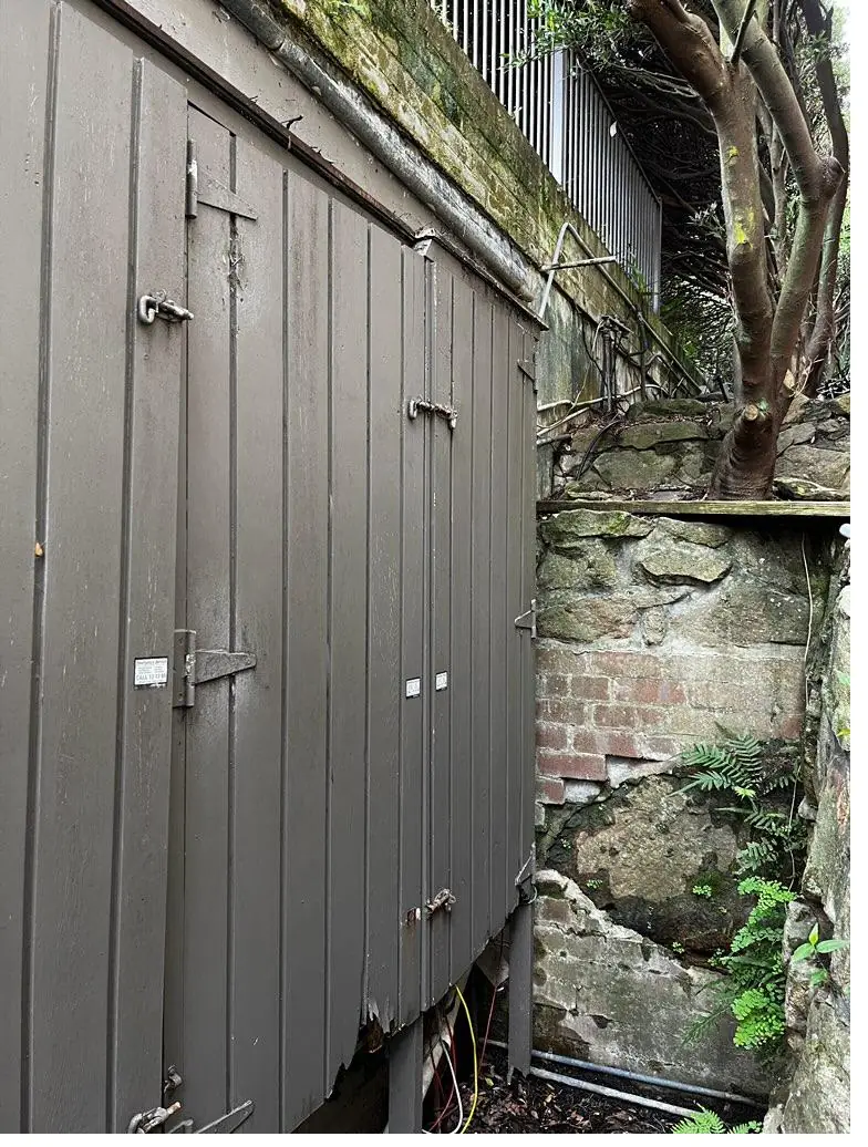 Old weathered timber meter cabinet closed, on an outdoor wall before replacement