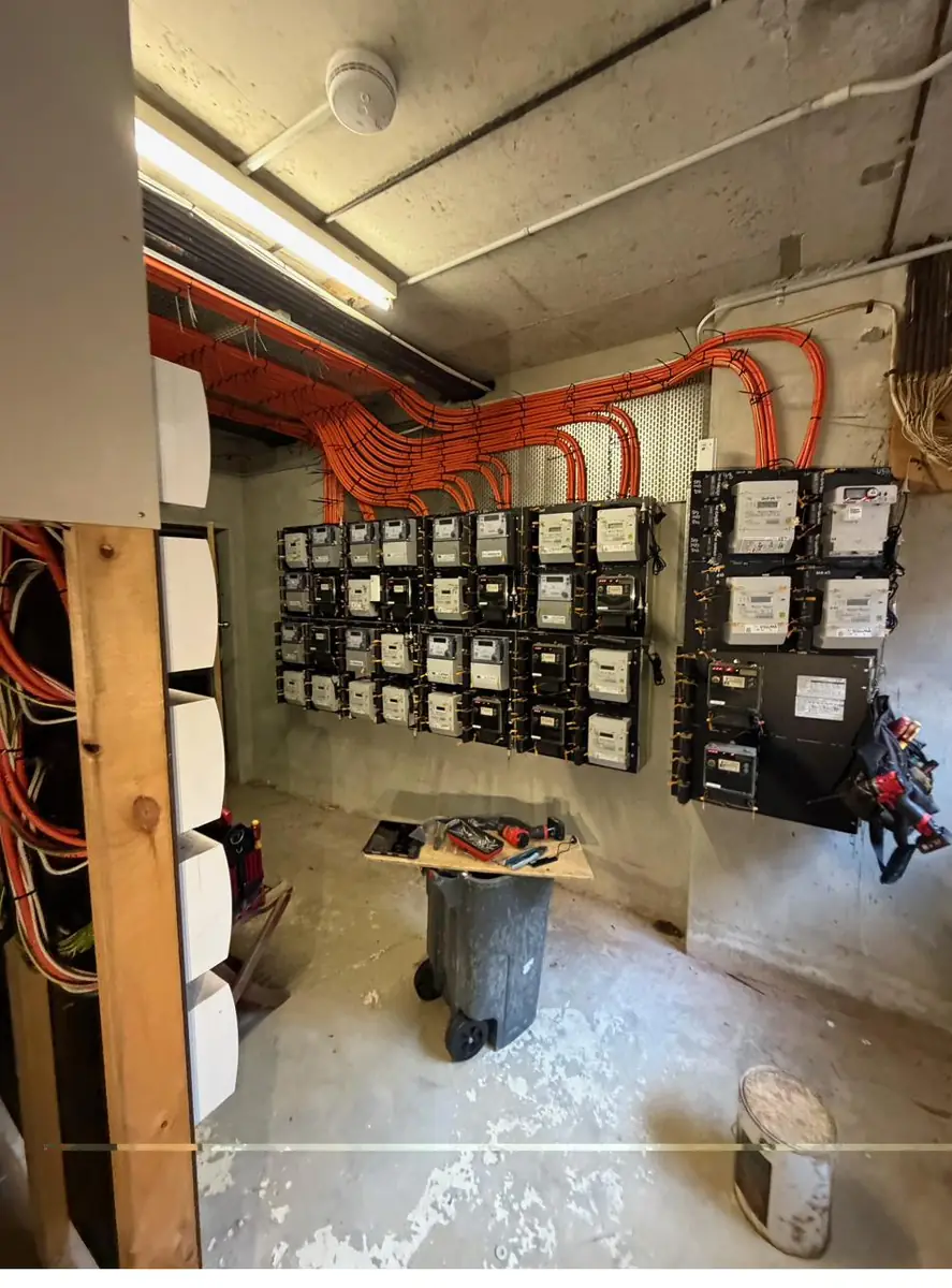 Rebuilt apartment building switchroom with new smart meters and orange submain conduits
